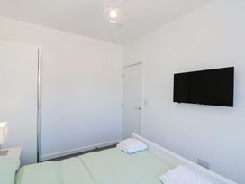 A bedroom with a bed, folded towels on the bed, a wall-mounted TV, a wardrobe, and a closed door at The Hideaway in Bempton near Flamborough