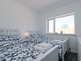 A bedroom with two single beds blue and white bedding and a lamp on a bedside table at The Hideaway in Bempton near Flamborough