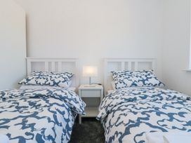A bedroom with two single beds and a lamp on a nightstand between them at The Hideaway in Bempton near Flamborough