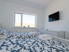 A bedroom with two single beds with patterned bedding a window and a wall mounted TV at The Hideaway in Bempton near Flamborough
