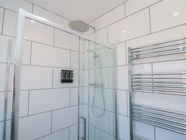 A tiled shower enclosure with a glass door a rainfall showerhead wall-mounted soap dispensers and a chrome towel radiator at The Hideaway in Bempton near Flamborough