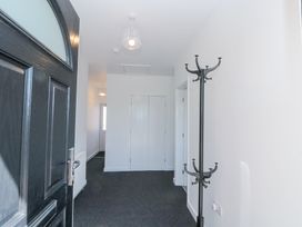 A hallway with a black coat rack a black front door and white double doors at The Hideaway in Bempton near Flamborough