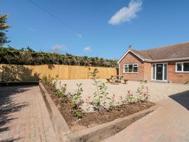 A gravel yard with a picnic table and small plants in a garden bed next to a brick house at The Hideaway in Bempton near Flamborough