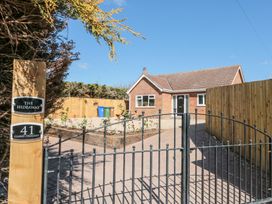 A brick house with a paved driveway behind a black iron gate at The Hideaway in Bempton near Flamborough