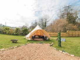 A garden with a bell tent two chairs a fire pit and a wooden fence at Bell tent 2 Camerton near Timsbury