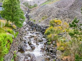 A stream flowing through rocks and vegetation at Swirral Edge Cottage in Glenridding