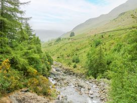 A river flowing through a valley surrounded by trees and hills at Swirral Edge Cottage Glenridding