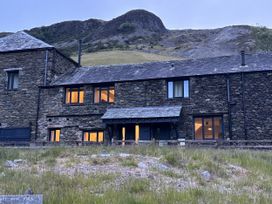An outdoor view of a stone building with windows at Swirral Edge Cottage in Glenridding