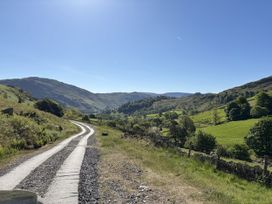 A winding road through hills and trees at Swirral Edge Cottage in Glenridding