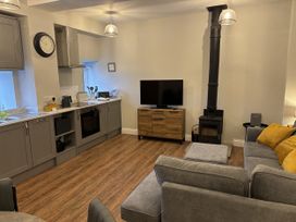 A kitchen and living room area with a sofa and television at Swirral Edge Cottage in Glenridding