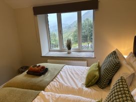 A bedroom with two beds and a window at Swirral Edge Cottage in Glenridding