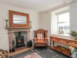 A sitting room with a fireplace and armchair at High Ickenthwaite Farmhouse in Ulverston
