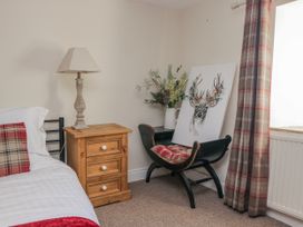 A bedroom with a bed, nightstand, lamp, chair, and painting at High Ickenthwaite Farmhouse Ulverston