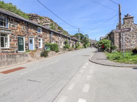 A street with stone houses and a road sign pointing to Ty Afon at Llys Emrys in Beddgelert