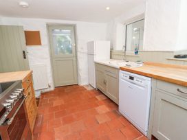 A kitchen with a stove wooden countertops a white dishwasher a white refrigerator a sink and a door at Llys Emrys in Beddgelert