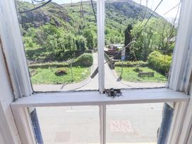 A view of a road park benches and green hillside seen through a window at Llys Emrys in Beddgelert