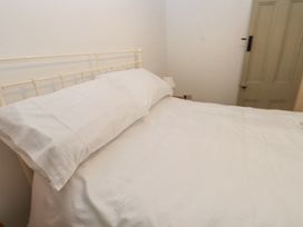 A bedroom with a bed with white bedding a bedside lamp and a closed door at Llys Emrys in Beddgelert