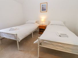 A bedroom with two single beds a wooden bedside table and a lamp at Llys Emrys in Beddgelert