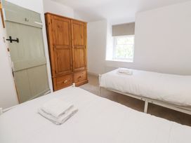 A bedroom with two single beds each with folded towels a wooden wardrobe and a window at Llys Emrys in Beddgelert