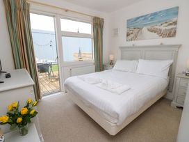 A bedroom with a double bed white bedding bedside tables lamps and a door leading to an outdoor seating area at Plimoth N8 in Yarmouth