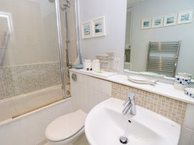 A bathroom with a white toilet a sink a bathtub with a shower and decorative items on a counter at Plimoth N8 in Yarmouth
