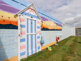 A beach hut with a mural and toys in an outdoor area at Plimoth N8 in Yarmouth