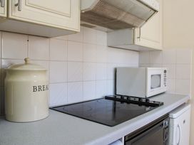 A kitchen with a cooker, microwave, and storage jar at 2 The Elms, Salcombe