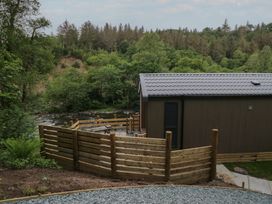 An outdoor area with a wooden building and fence by a river at Dubs Luxury Family Pod in Keswick