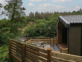 An outdoor area with a deck and table near a river at Dubs Luxury Family Pod in Keswick