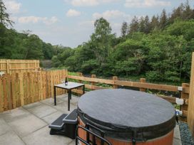 An outdoor area with a hot tub and table at Woof Luxury Family Pod in Keswick