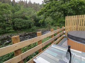 An outdoor area with a hot tub and a view of a stream at Woof Luxury Family Pod in Keswick