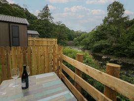 An outdoor seating area with a table, glasses, and a bottle at Woof Luxury Family Pod in Keswick