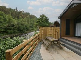 An outdoor area with a table and bench near a river at Lingy Luxury Family Pod in Keswick