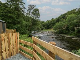 A river surrounded by trees and a wooden fence at Lingy Luxury Family Pod in Keswick