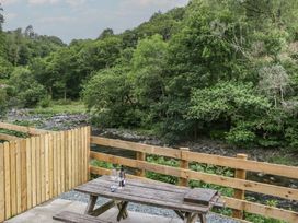 An outdoor seating area with a table and chairs near a river at Sail Luxury Family Pod in Keswick