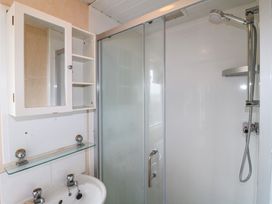 A bathroom with a shower enclosure a white sink and a wall-mounted cabinet with mirror at Beatrice's Static Caravan in Spalding