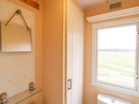 A bathroom corner with a white cabinet mirror window and toilet at Beatrice's Static Caravan in Spalding