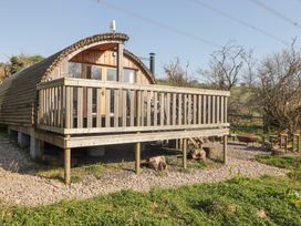 A wooden cabin with a deck and outdoor seating area with fire pit at Cabanau Bach in Bedwas
