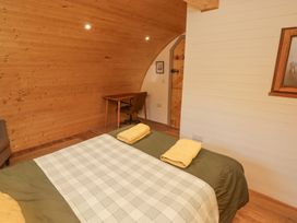 A bedroom with a bed with yellow towels on it a wooden desk and chair and a wooden door at Cabanau Bach in Bedwas