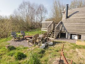 An outdoor area with wooden chairs and a fire pit near a wooden cabin with stairs at Cabanau Bach in Bedwas