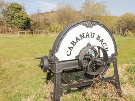 A metal industrial machine with a large wheel and the name Cabanau Bach in a grassy outdoor area in Bedwas