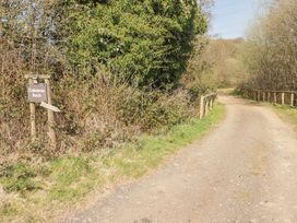 A dirt road with wooden fences on the side and a signpost saying Cabanau Bach among trees and bushes at Cabanau Bach in Bedwas