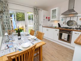 A kitchen with a dining table set for six and a bottle of prosecco next to a window at Plimoth N9 in Yarmouth