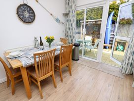 A dining area with a wooden table and chairs set for four next to sliding glass doors opening to an outdoor patio at Plimoth N9 in Yarmouth