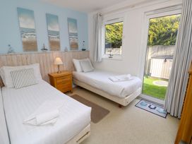 A bedroom with two single beds a wooden nightstand a lamp and a glass door leading outside at Plimoth N9 in Yarmouth