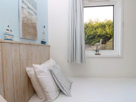 A bedroom with a bed pillow and cushions beside a window with curtains and decorative sailboats at Plimoth N9 in Yarmouth
