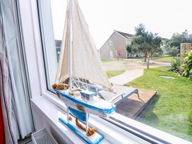 A model sailboat on a windowsill with a garden and houses visible outside at Plimoth N9 Yarmouth