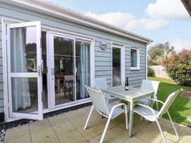 An outdoor patio with a table and four chairs next to a house with sliding and open doors at Plimoth N9 in Yarmouth