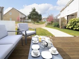 An outdoor seating area with a gray sofa and chair and a table set with cups plates and a teapot at Plimoth N9 in Yarmouth