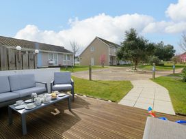 A patio with outdoor seating and a table set for tea outside houses with lawn and trees at Plimoth N9 in Yarmouth